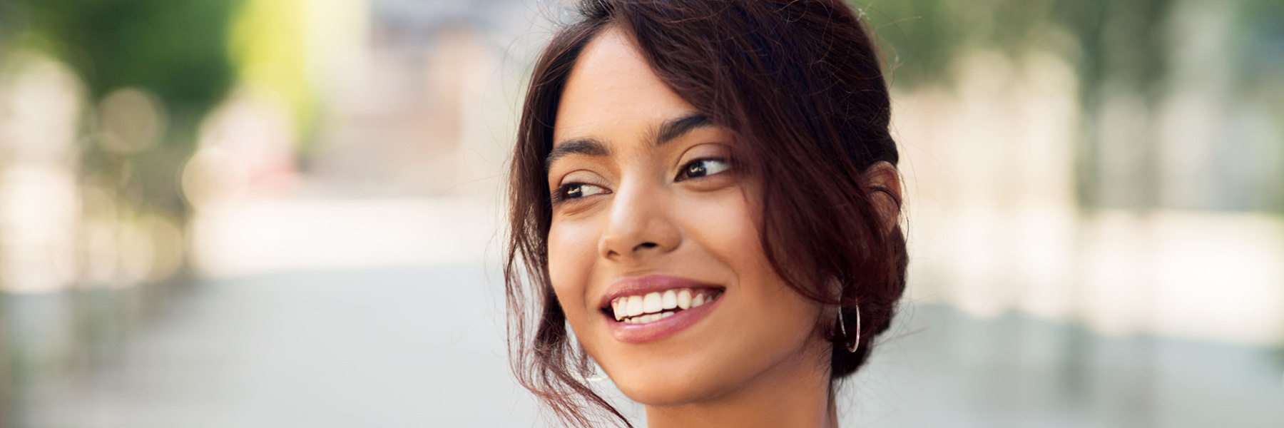 Young woman smiling confidently outdoors, healthy white teeth after dental crown treatment