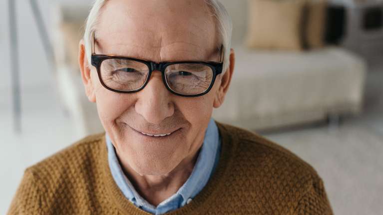 Old man wearing eyeglasses smiling with his implant in Mona Vale