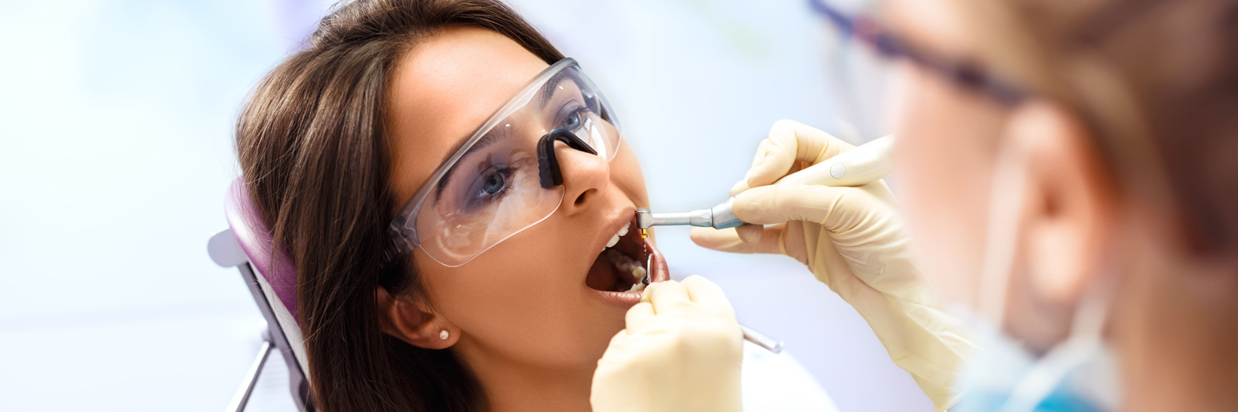 Dentist performing a professional dental clean on a female patient in a dental chair